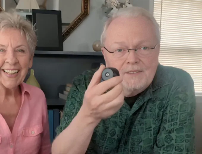 Older couple at home, the man holding a PebblePeek camera