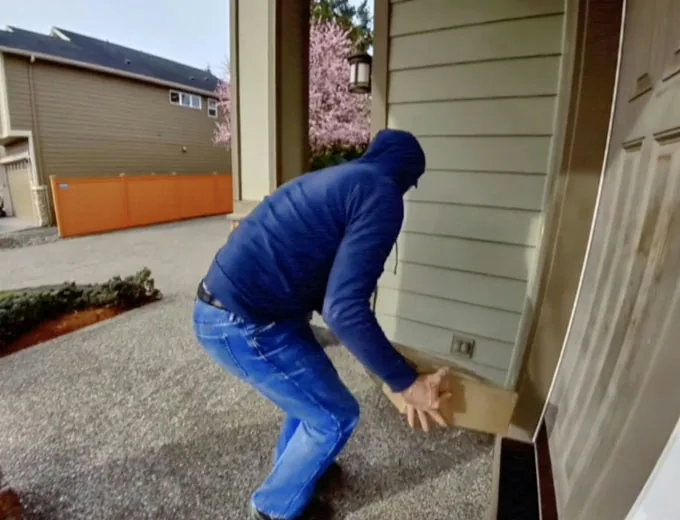 Camera clip of a person picking up a parcel left at a front door